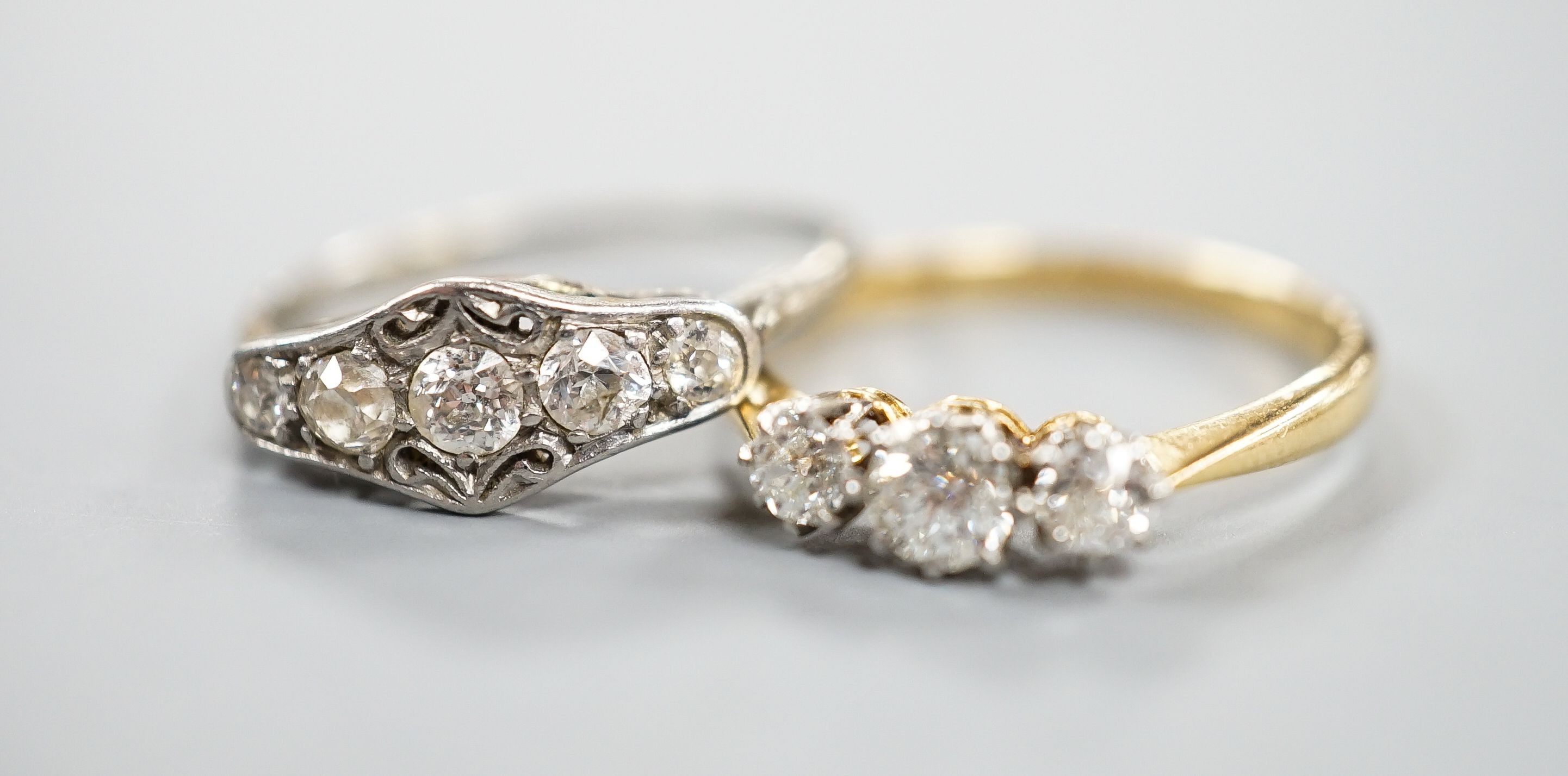 An 18ct and three stone diamond ring, size M and a white metal and graduated five stone diamond set half hoop ring, size M, gross weight 3.8 grams.